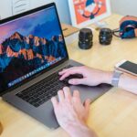 MacBook Pro włączony obok białego ceramicznego kubka